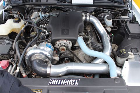 2004 Ford Crown Victoria - Close-up of a modified engine bay a prominent supercharger and custom intake piping.
