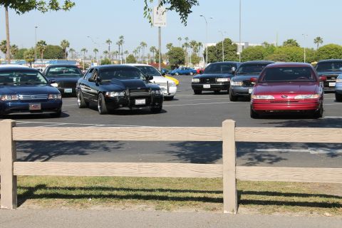 2004 Ford Crown Victoria - A red 2004 Ford Crown Victoria is parked in a lot with several other cars under a clear sky.