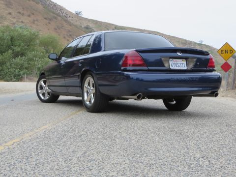 2003 Mercury Marauder - A dark blue 2003 Mercury Marauder sedan is parked on a road with a hill in the background.