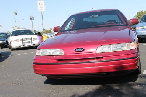 2004 Ford Crown Victoria - A red Ford Crown Victoria is parked in a lot, with other vehicles visible.