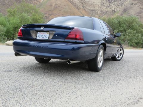2003 Mercury Marauder - Rear view of a 2003 Mercury Marauder sedan parked on a road with hills in the background.