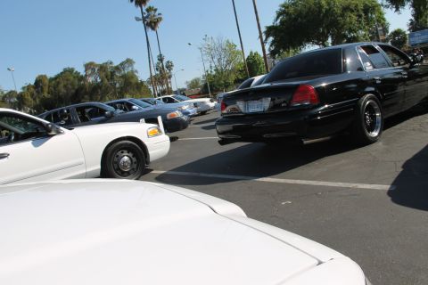 2004 Ford Crown Victoria - A black 2004 Ford Crown Victoria is parked in a lot, showing its rear end and custom wheels.
