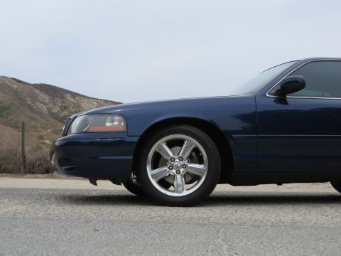 2003 Mercury Marauder - Side view of a dark blue 2003 Mercury Marauder showing the front wheel and fender.