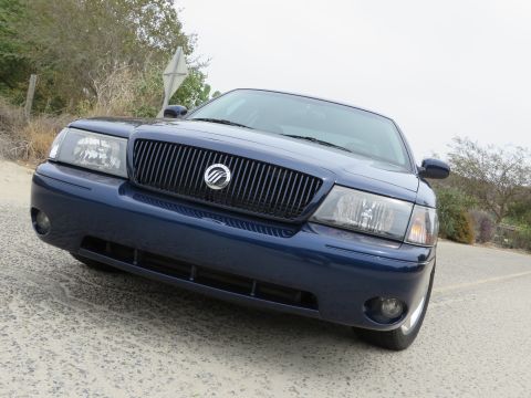 2003 Mercury Marauder - The front of a dark blue 2003 Mercury Marauder is shown parked on a road with trees in the background.