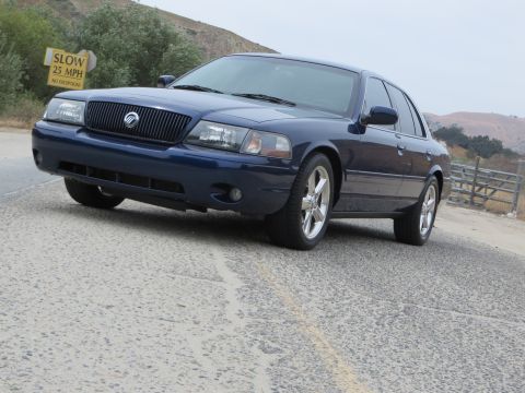 2003 Mercury Marauder - A dark blue 2003 Mercury Marauder is parked on a road with a speed limit sign in the background.