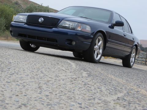 2003 Mercury Marauder - A dark blue sedan is parked on a road with a hilly background.