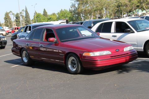 2004 Ford Crown Victoria - A maroon Ford Crown Victoria is parked in a lot, showing its front three-quarter view with aftermarket wheels.
