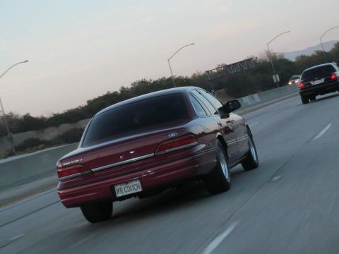 2004 Ford Crown Victoria - A maroon 2004 Ford Crown Victoria is seen from behind on a highway, with another car in the distance.