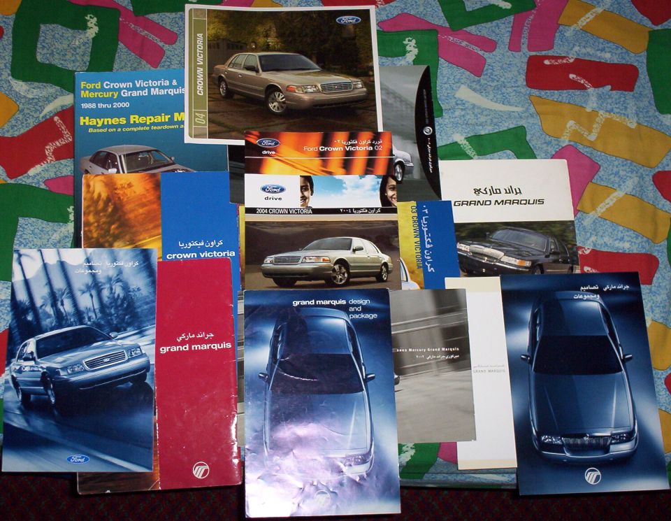 Mercury Grand Marquis and Ford Crown Victoria brochures and Haynes manual spread on a patterned cloth