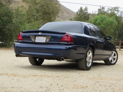 2003 Mercury Marauder - The rear view of a dark blue 2003 Mercury Marauder sedan parked on a dirt road.