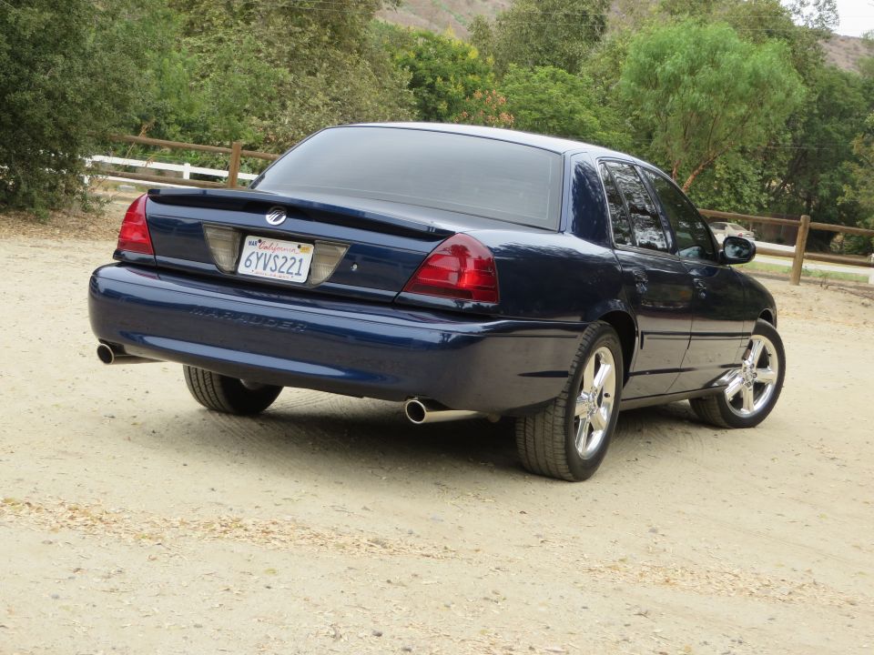 Rear 3/4 view of a dark blue 2003 Mercury Marauder parked on a dirt road