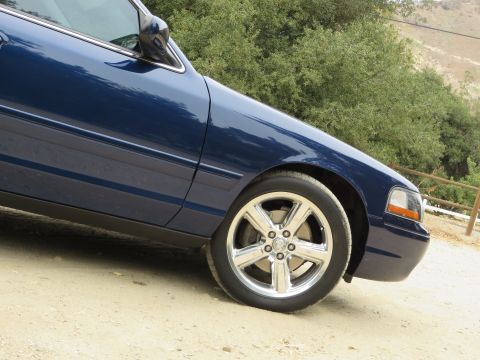 2003 Mercury Marauder - The front quarter panel and wheel of a blue 2003 Mercury Marauder are visible.