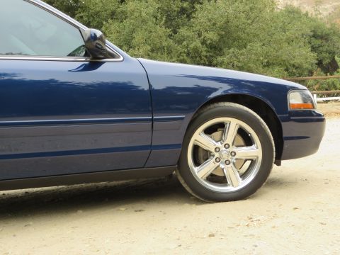 2003 Mercury Marauder - The front quarter panel and chrome wheel of a blue 2003 Mercury Marauder are visible.
