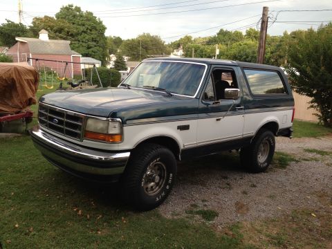 1994 Ford Bronco - This two-tone green and white 1994 Ford Bronco is shown from a three-quarter front perspective, with its grille providing year identificati…
