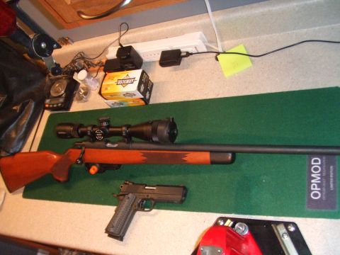 1996 Ford Bronco - A rifle and handgun are laid out on a green mat next to a power strip and ammunition boxes.
