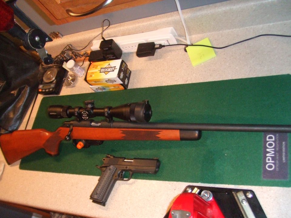 Bolt-action rifle with scope and a semi-automatic pistol on a green mat
