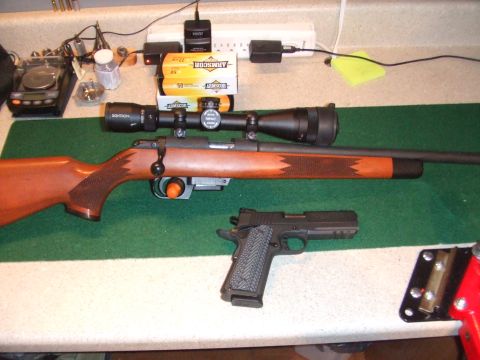 1996 Ford Bronco - A rifle with a scope and a handgun are laid out on a green mat next to ammunition and electronic chargers.