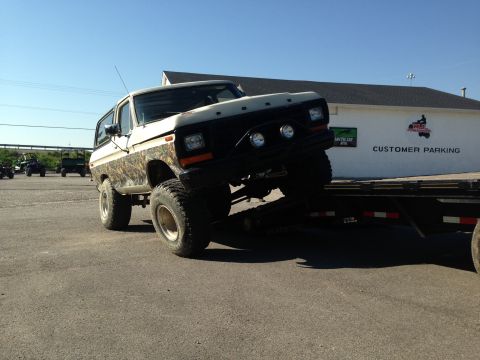 1994 Ford Bronco - This lifted Ford Bronco is being loaded onto a trailer, with other vehicles visible in the background.