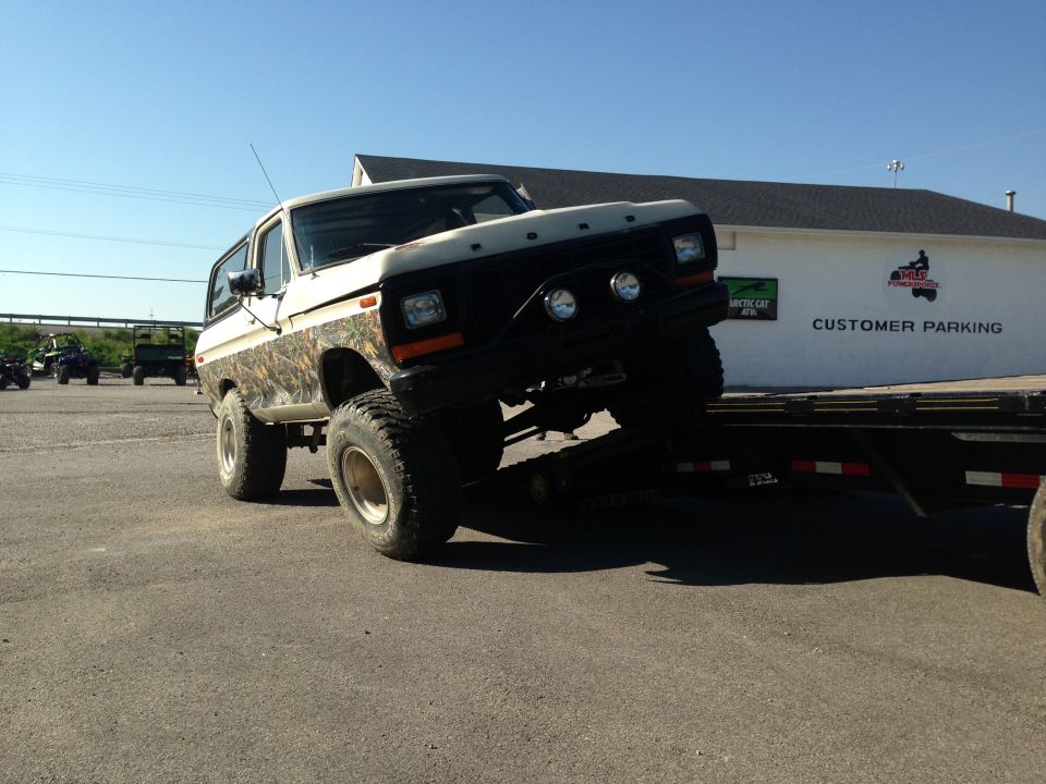 White and camouflage Ford Bronco on a trailer, front-right view