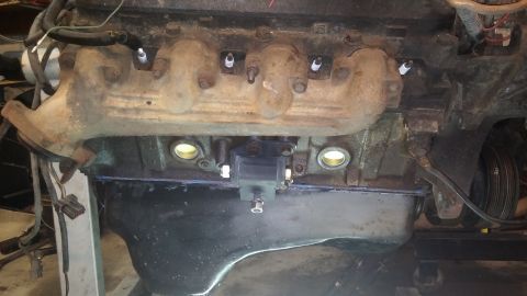 1995 Ford Bronco - Close-up view of an engine block, showing the exhaust manifold, spark plugs, and ignition coil.
