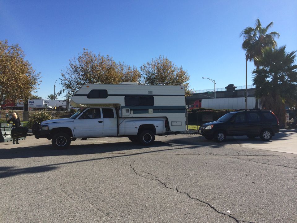 White pickup truck with a camper shell parked next to a black SUV