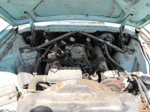 1963 Ford Thunderbird - The engine bay of a 1963 Ford Thunderbird reveals a V8 engine with a carburetor, showing signs of significant wear and tear.
