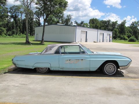 1963 Ford Thunderbird - A light blue 1963 Ford Thunderbird coupe with a white roof is parked outside a commercial building.