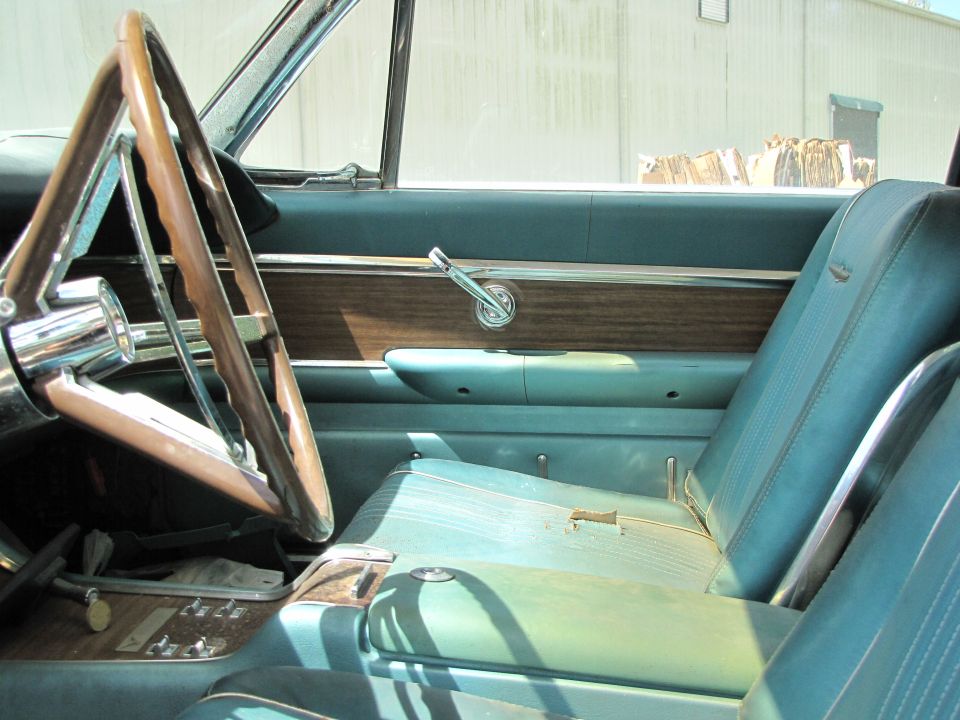 1963 Ford Thunderbird interior showing turquoise seats, woodgrain trim, and steering wheel