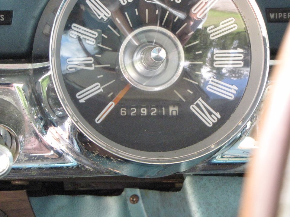 Car dashboard showing a speedometer with a needle pointing to 20, odometer reading 62921, and chrome trim