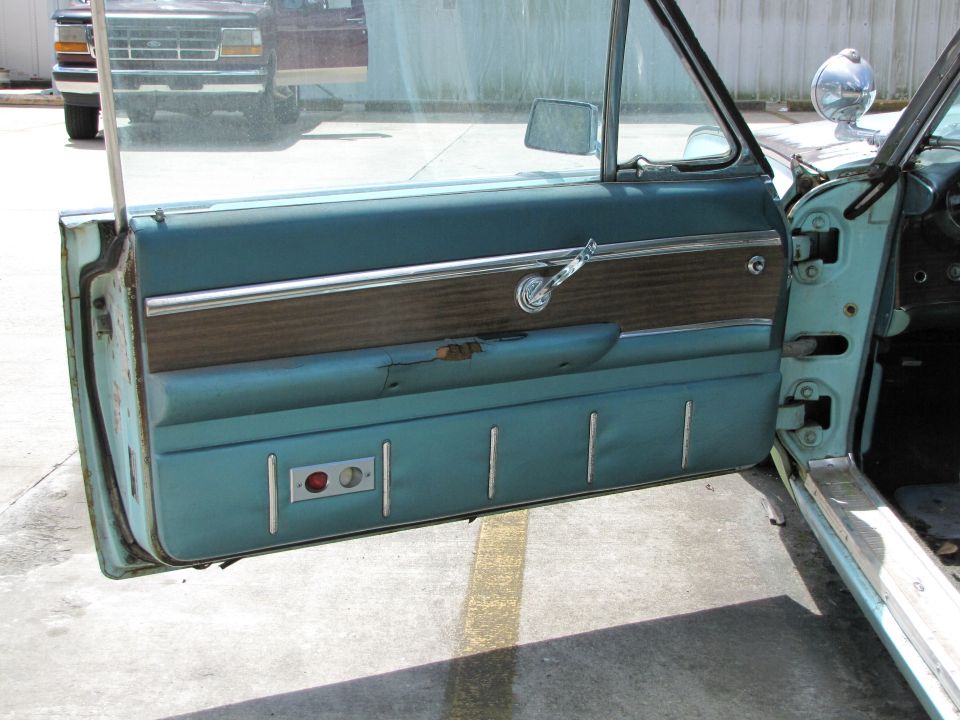 Interior door panel with wood grain trim, chrome handle, and two buttons