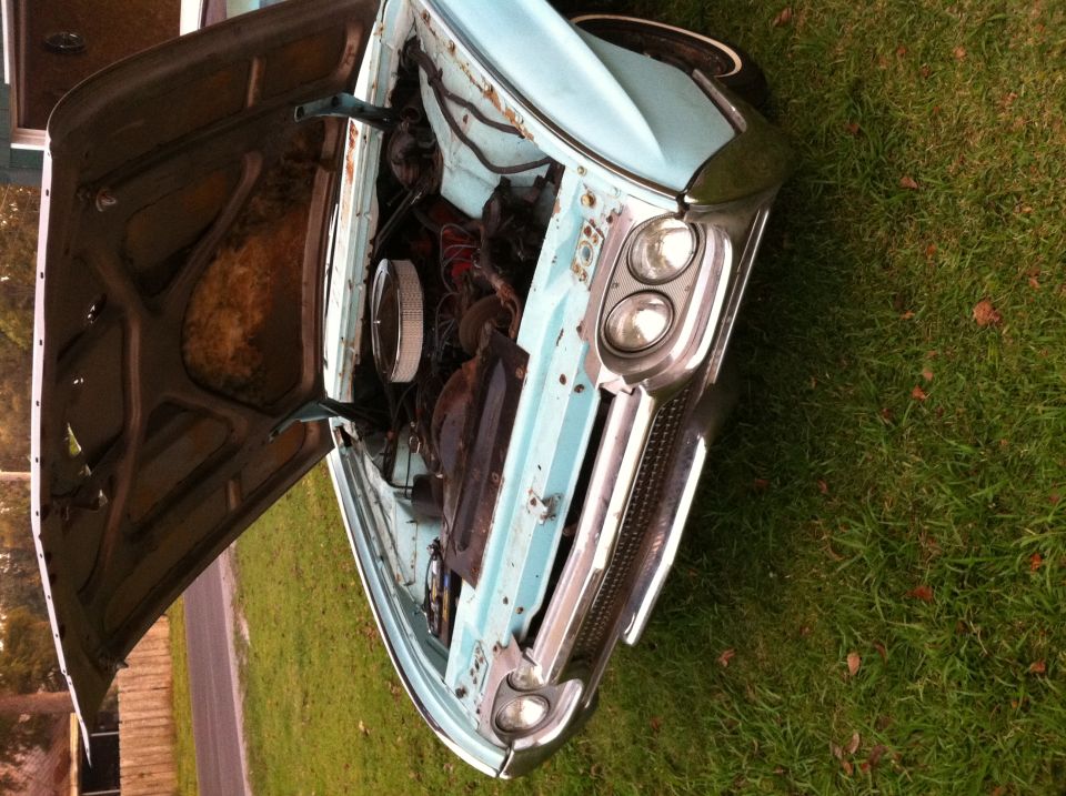 light blue classic car, hood up, showing engine bay. Grille and dual headlights visible