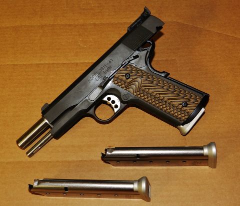 1996 Ford Bronco - A handgun and two magazines are displayed on a textured brown background.