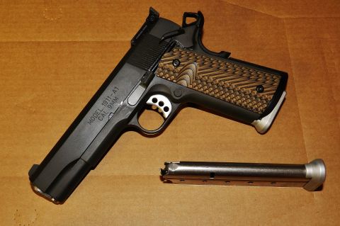 1996 Ford Bronco - A black 1911-A1 pistol chambered in 9mm is shown with its magazine, resting on a brown surface.