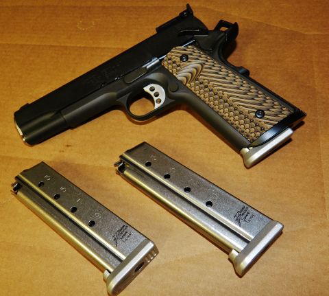 1996 Ford Bronco - A handgun with two spare magazines is displayed on a textured brown background.