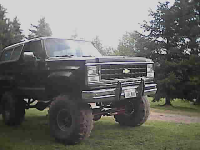 Black lifted Chevrolet Blazer on large tires parked on grass, 3/4 front view