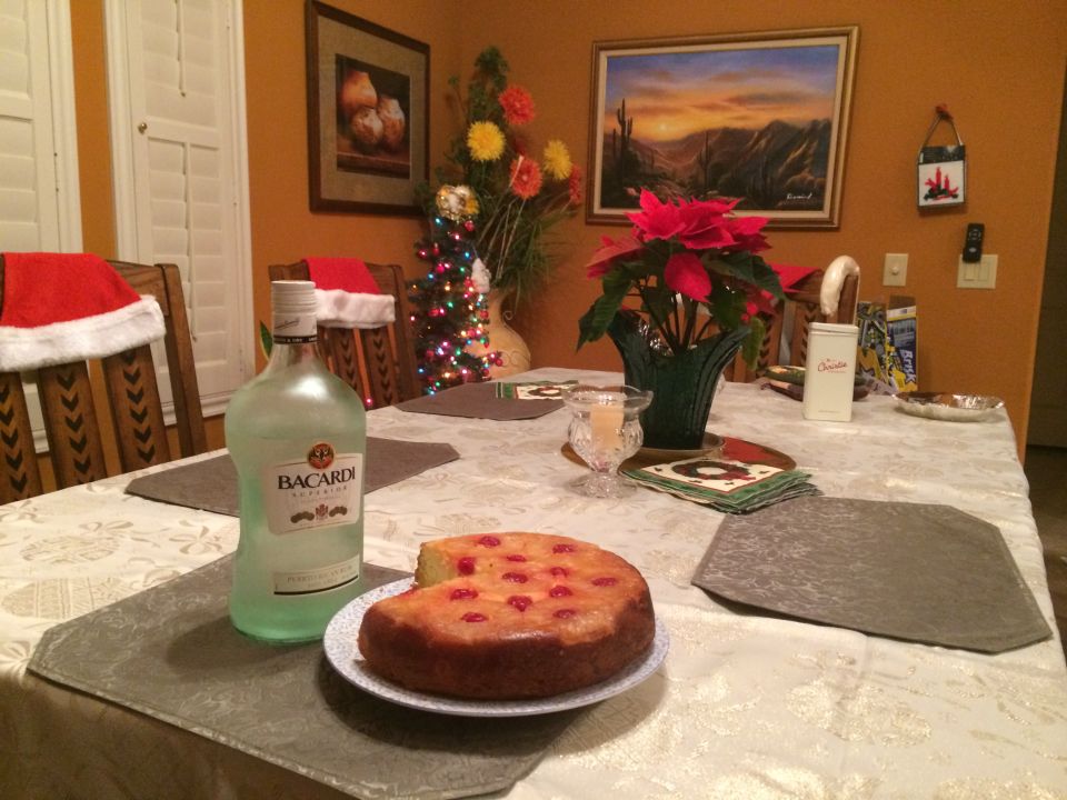 Christmas dinner table with Bacardi bottle, upside-down cake, and festive decorations