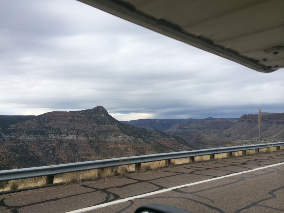 Mountain landscape with a road and guardrail under a cloudy sky