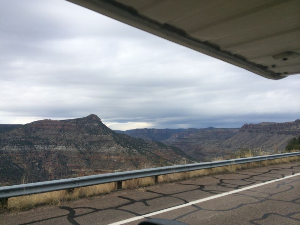 View of layered mountains and a cloudy sky from a vehicle