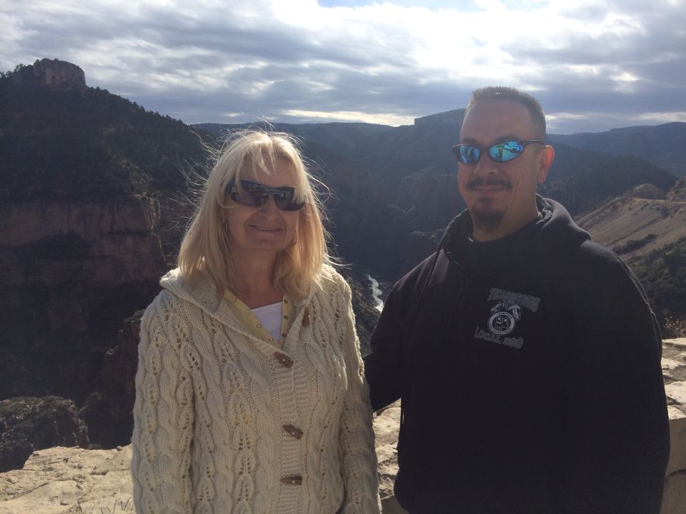 Couple posing for a photo at a scenic overlook with a canyon and river in the background