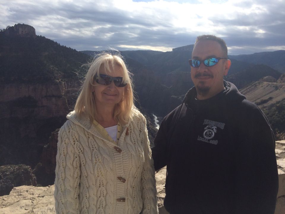 Couple posing for a photo in front of a vast canyon with a river below and mountains in the distance