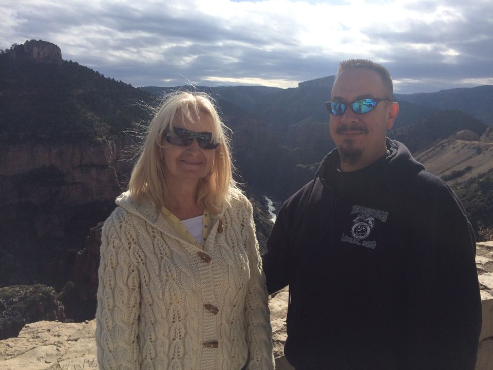 Couple posing for photo at a canyon overlook with mountains and a river in the background