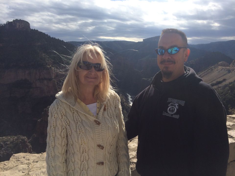Couple standing on a cliff overlooking a canyon, with a river below