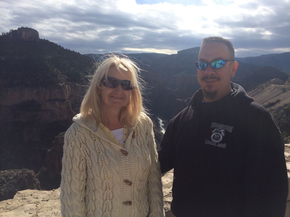 Woman and man stand on cliff edge with canyon and river below