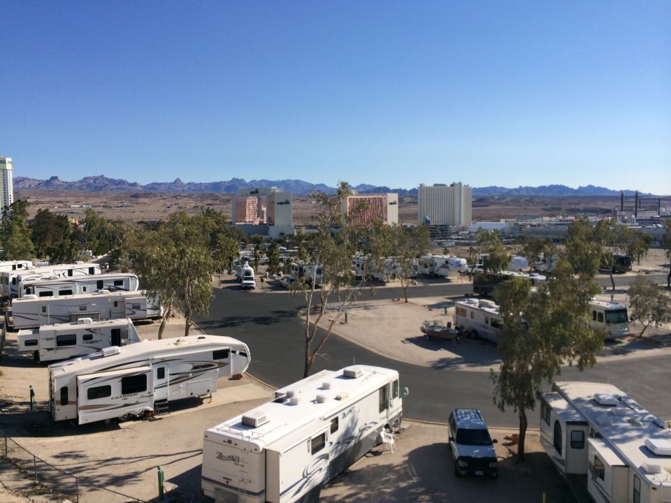RV park with many RVs parked, some buildings and mountains in the distance