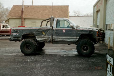 1979 Ford Bronco - Modified pickup truck with oversized tires and a roll bar is parked outside a building.