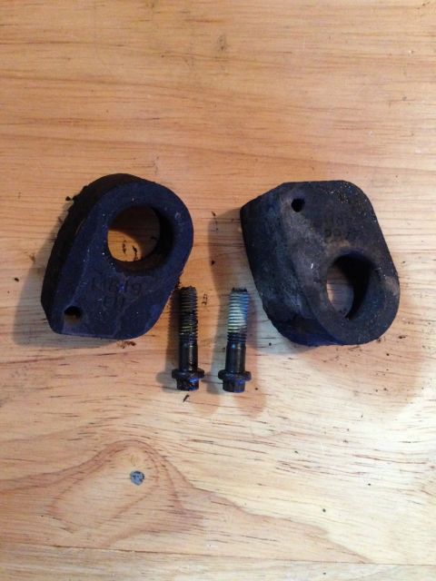 1995 Ford Bronco - Two rubber body mounts and two bolts are laid out on a wooden surface.