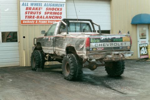 1979 Ford Bronco - This heavily modified Chevrolet pickup truck is parked outside a repair shop.