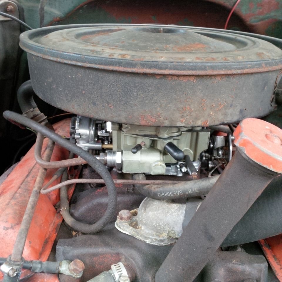 Close-up of a carburetor on an engine, with air cleaner housing above