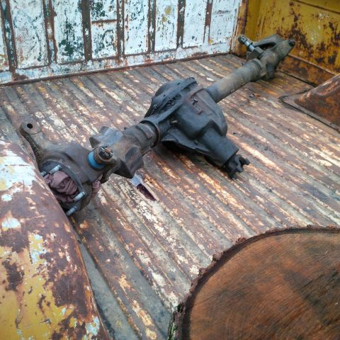 1978 Ford Bronco - A rear axle assembly rests in the weathered bed of a truck, showing signs of age and use.