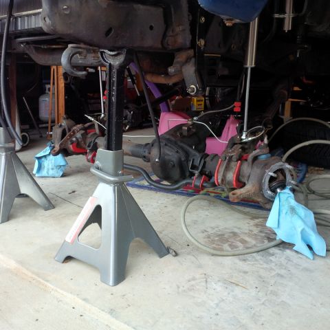 1978 Ford Bronco - Close-up of vehicle suspension components being worked on, supported by jack stands.